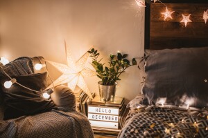 Nighttime shot of a cozy bedroom with Christmas lights on the bed and lounge chair