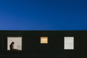 Exterior bright night shot of a building with a window view of a girl using her laptop 