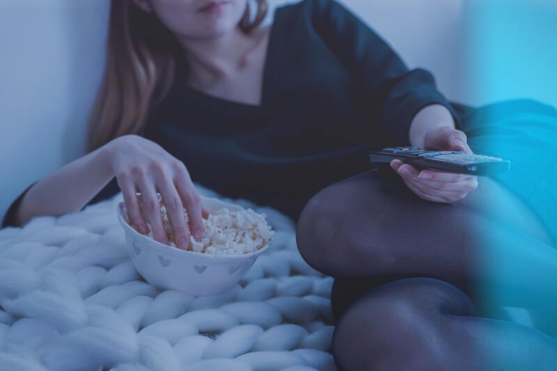 Person eating popcorn in bed, after dinner