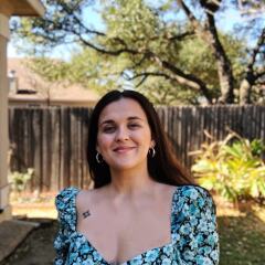 Headshot of writer Ada Ciuca. She's standing outside and wearing a floral top.