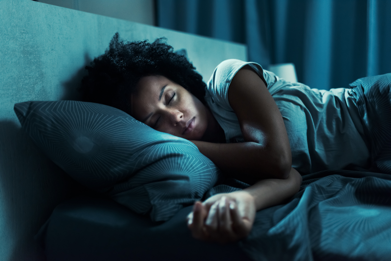 A woman asleep in bed with a blue filter set over the picture.