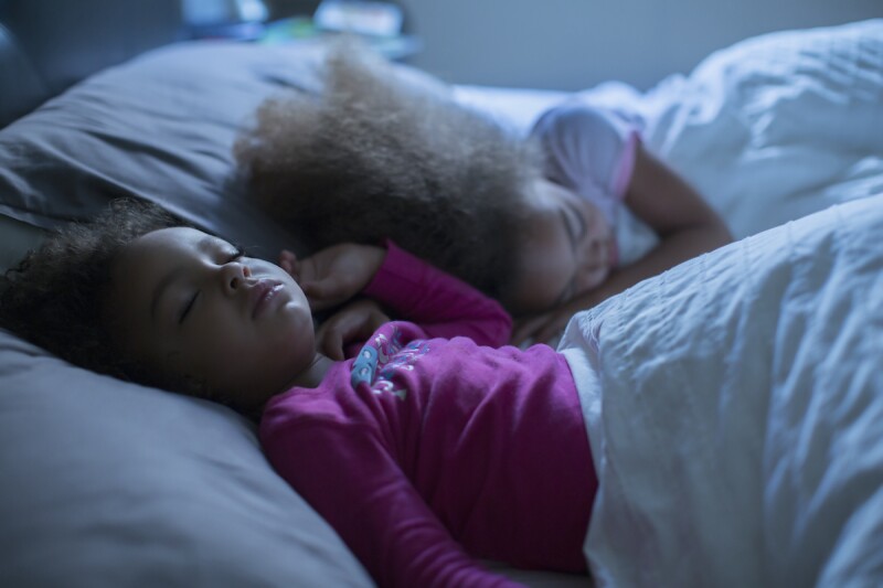 Two girls asleep in bed after their bedtime routine