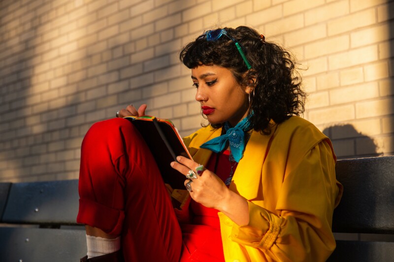 Woman wearing bold, colorful clothes, journaling her dreams 