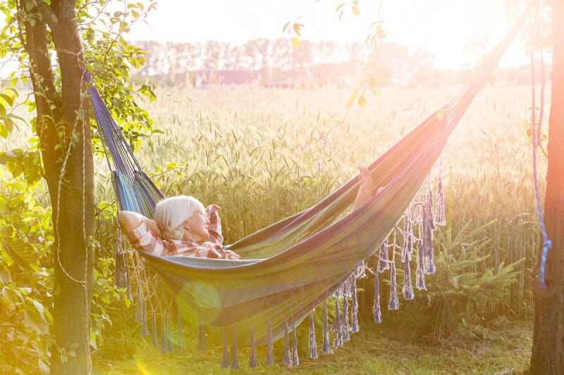 A woman laying in a hammock out in a field takin a nap