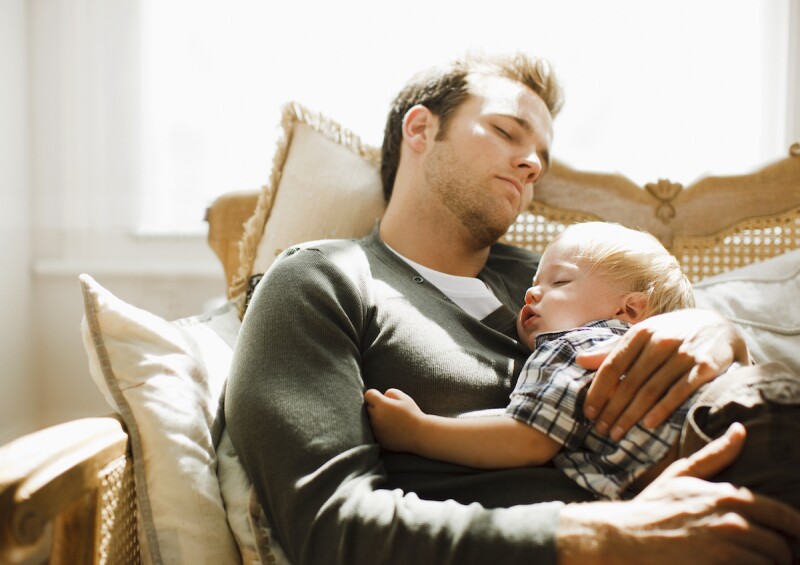 Father falling asleep for a nap with toddler in his arms after an attempt at sleep training