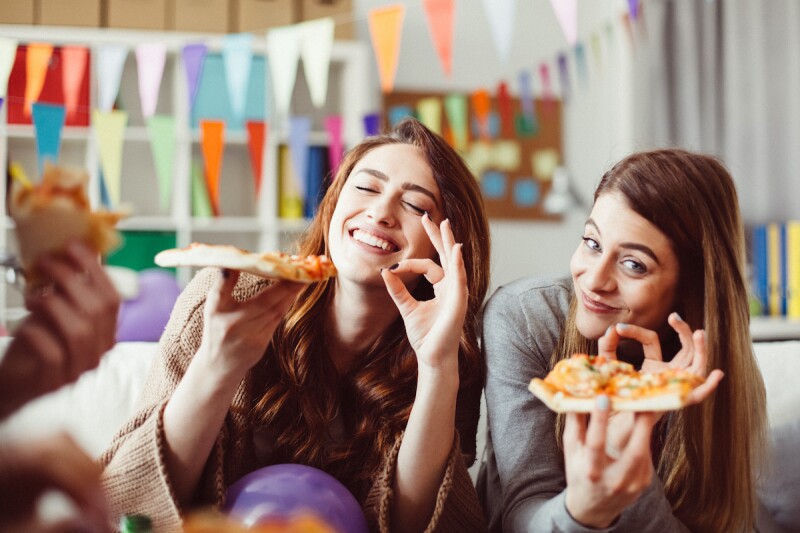 Two adults eating delicious pizza at a slumber party