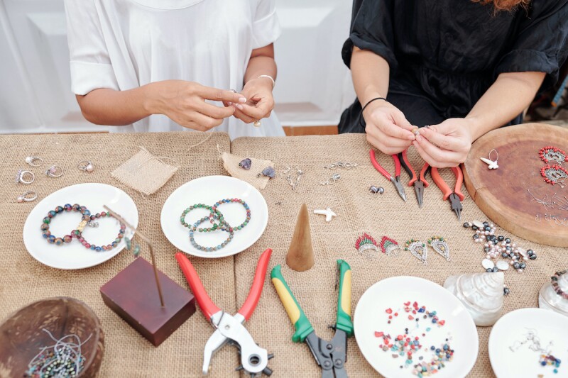 Two people using beads and string to make bracelets as a slumber party activity