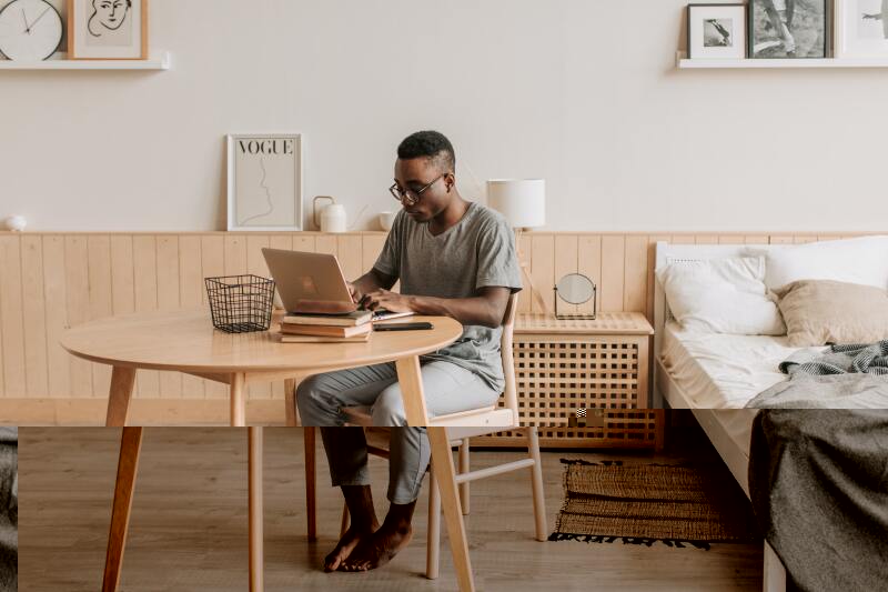 Man working on a laptop at his desk near his bed